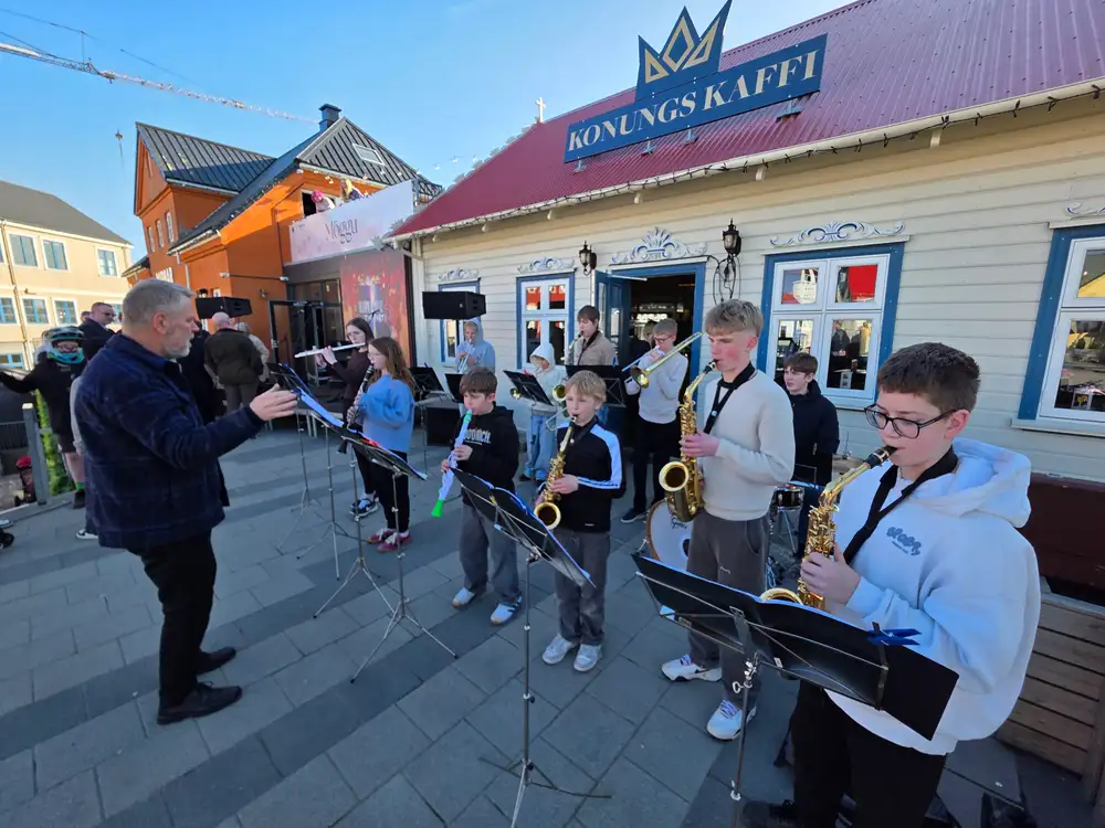 Lúðrasveitin er samansett af ýmsum og spilar úti í sólinni.