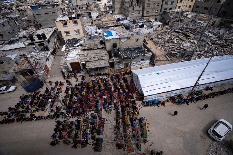 Íbúar Rafah-borgar á Gaza biðjast fyrir nærri húsarústum.