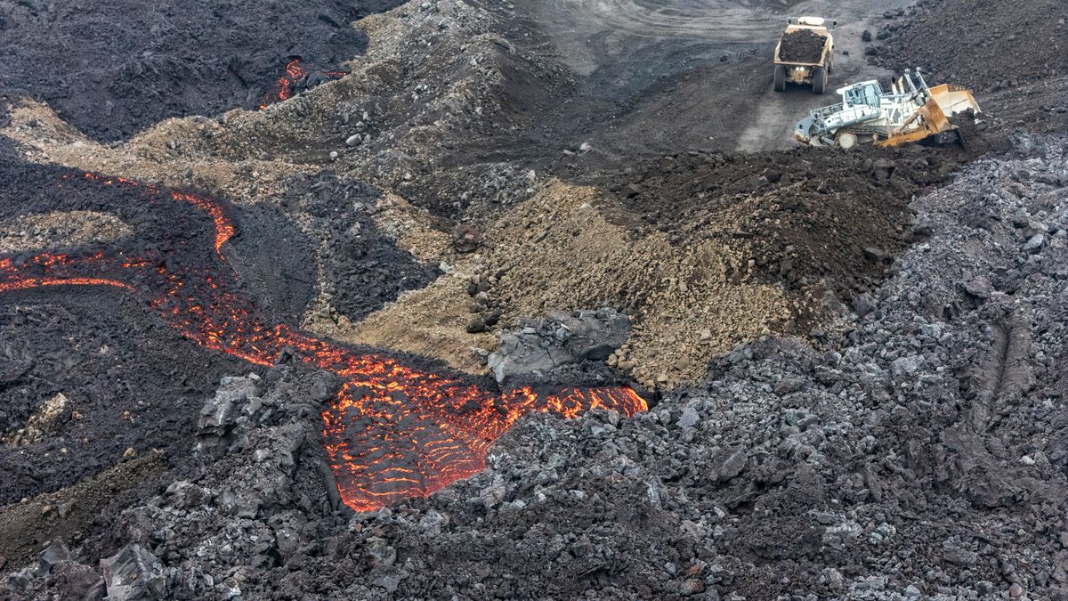 Machines work to slow the lava's progress with earthen dams and cooling water.