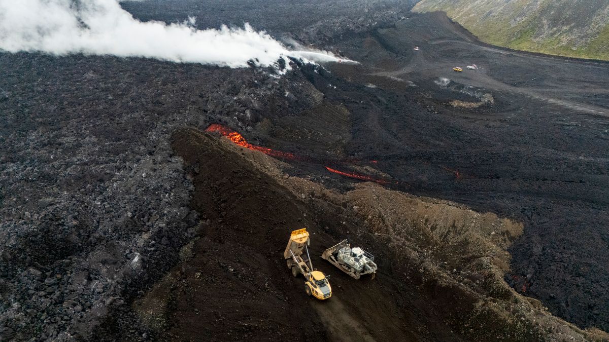 Machines work to slow the lava's progress with earthen dams and cooling water.