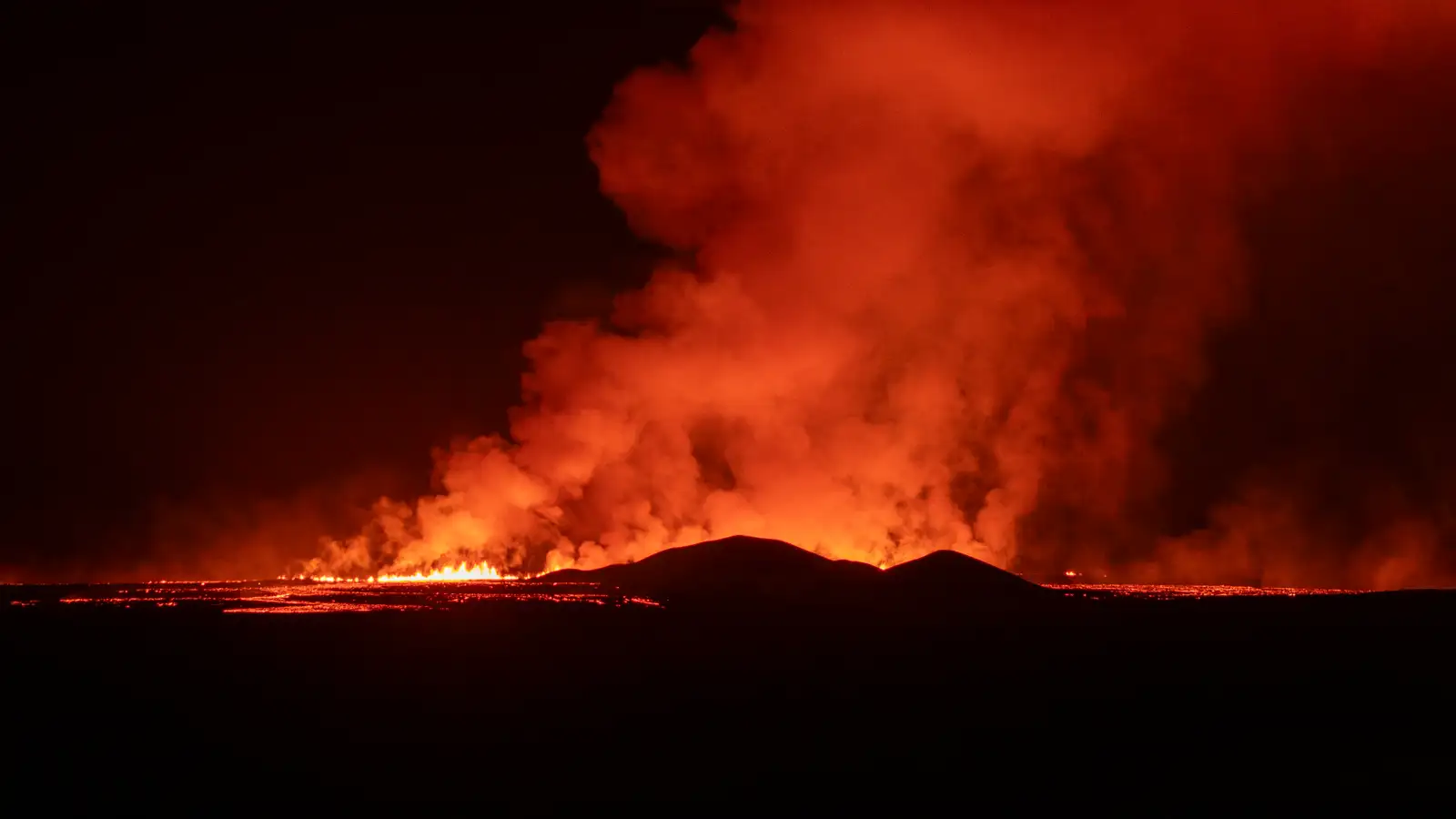 Foto der Eruptionszentren am Sundhnúksgíga in der Nacht vom 21. November 2024. In pechschwarzer Dunkelheit ist glühende Lava zu sehen und der Krater sieht im Schein rötlich aus.