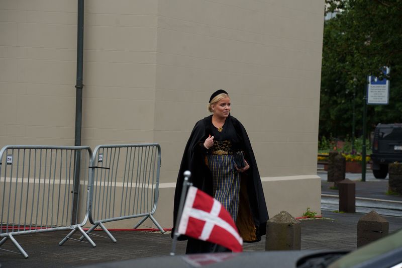 Eine Frau in Nationaltracht und der dänischen Flagge an der Kathedrale.