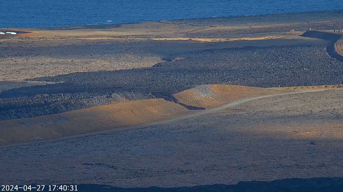 The image shows a tongue of lava stretching over the defense wall L12 and descending towards a dirt road below.