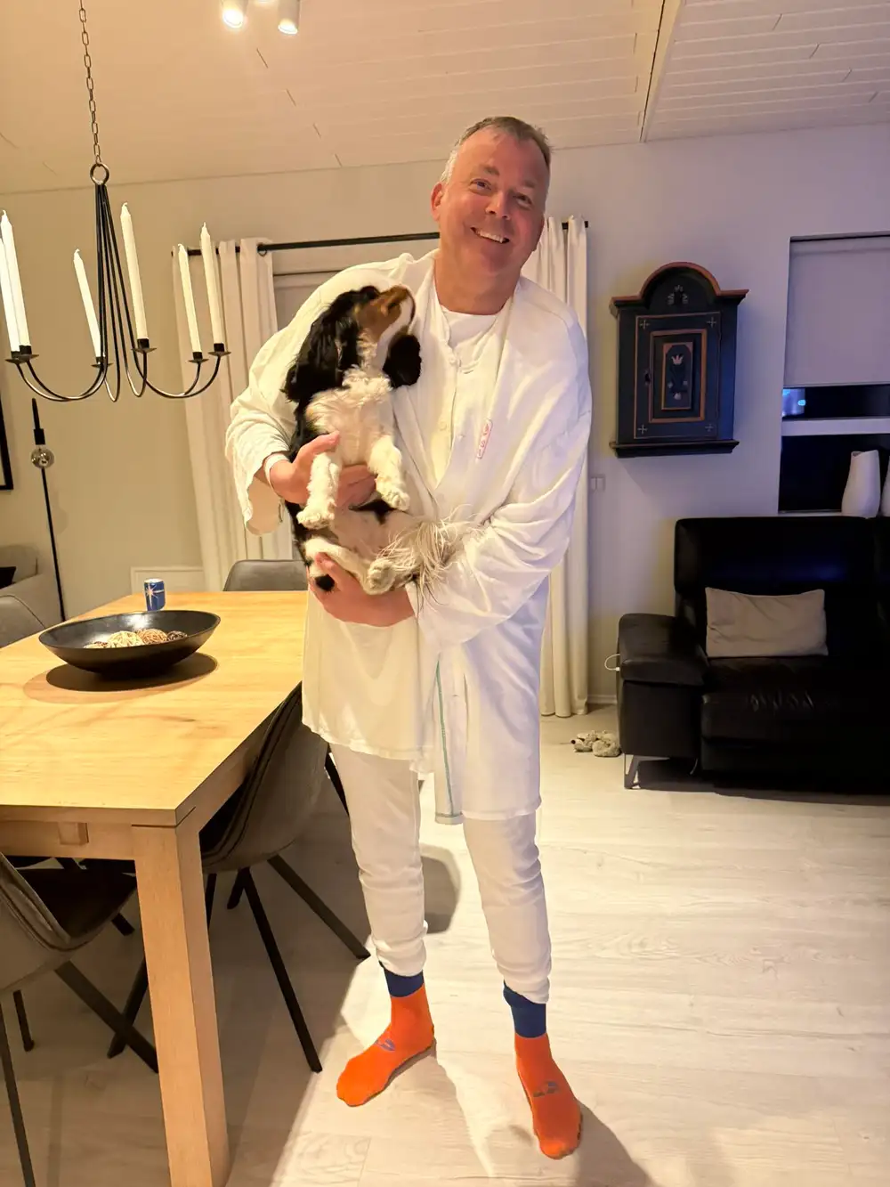 Jón Pétur Zimsen með hundinn Kviku í fanginu, klæddur fötum sem hann fékk á Landspítalanum eftir að hafa lent í sjónum og ofkælst.