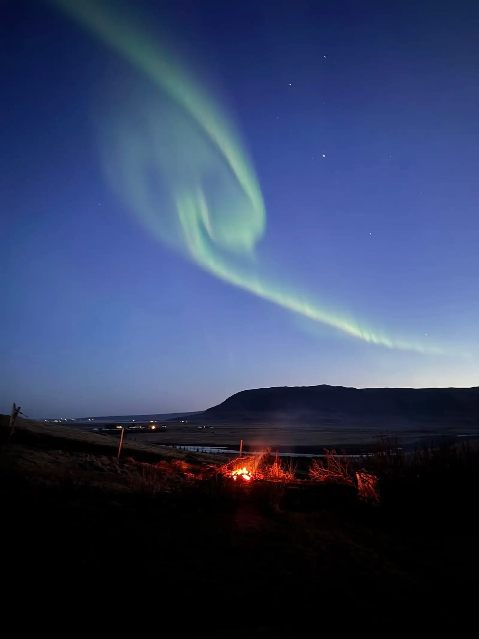 Fatabrennan á jörðu niðri og norðurljósin á himni.