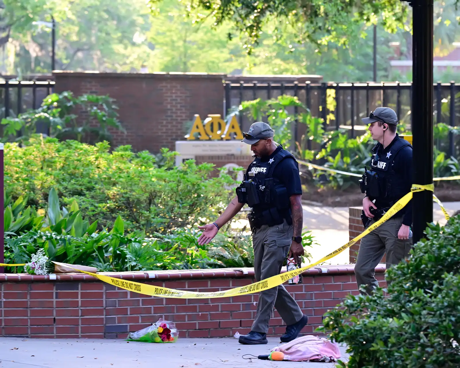 epaselect epa12038061 Police officers walk past flowers left at the scene after a gunman shot multiple people earlier today at Florida State University fire In Tallahassee, Florida , USA, 17 April 2025. According to a statement by Florida State University Police Chief Jason Trumbower, a person, who police suspect of being a student, shot multiple people today near the school’s student union, killing two people and injuring five people.  EPA/DON HAYES