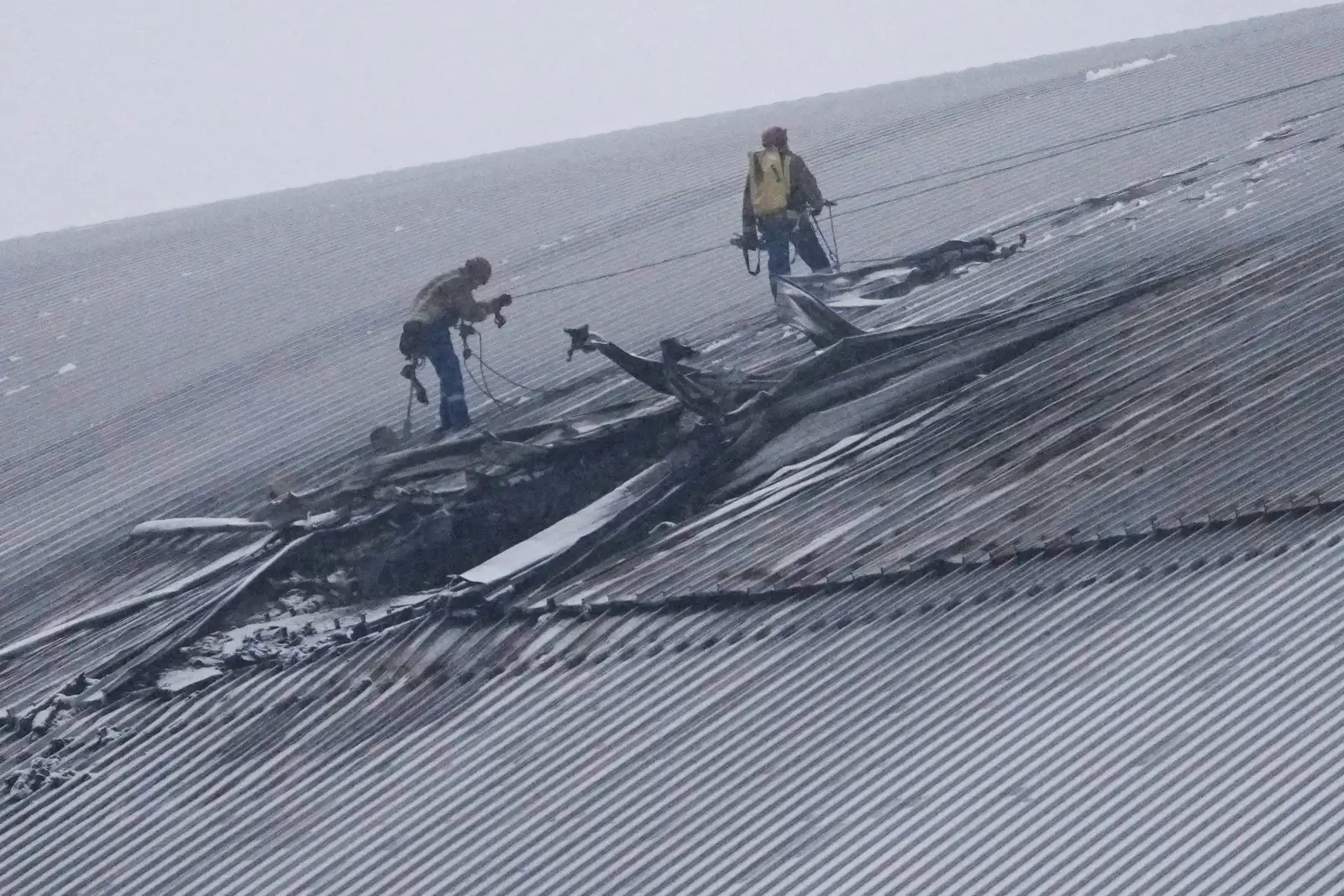 FILE - Workers examine the damage to the roof of the New Safe Confinement structure, which was built to contain the radioactive remains of Reactor No. 4 at the Chernobyl nuclear power plant, following what Ukrainian officials said was a Russian drone attack in Chernobyl, Ukraine, Feb. 14, 2025. (AP Photo/Efrem Lukatsky, File)