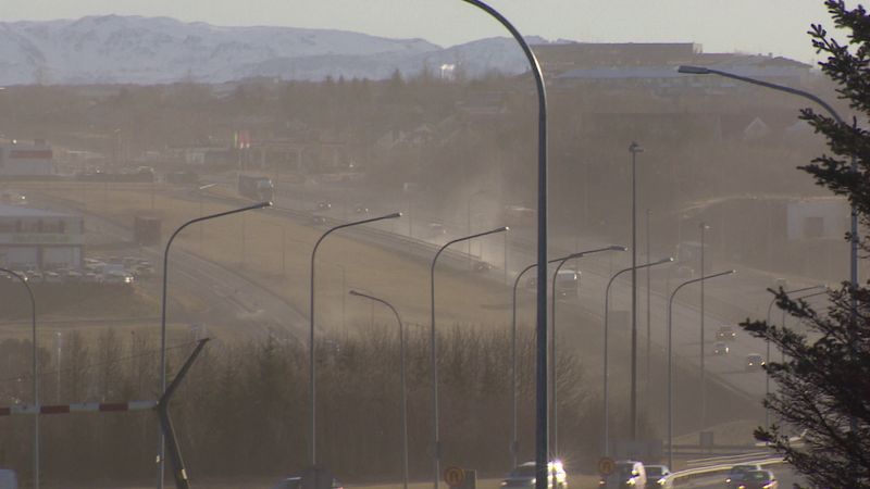 Mynd sem sýnir mikið svifryk í lofti í Reykjavík. Hún er tekin austur Miklubraut, upp Ártúnsbrekku. Fjöldi bíla ekur um brekkuna. Bílarnir sjást naumast sökum ryks. Bjart er í veðri en brúnleit móða yfir öllu.