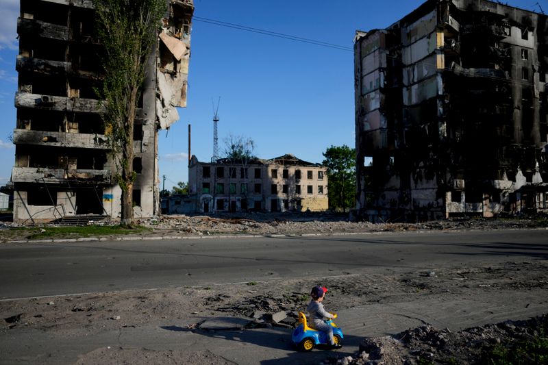 A boy plays in front of houses ruined by shelling in Borodyanka, Ukraine, Tuesday, May 24, 2022. (AP Photo/Natacha Pisarenko)