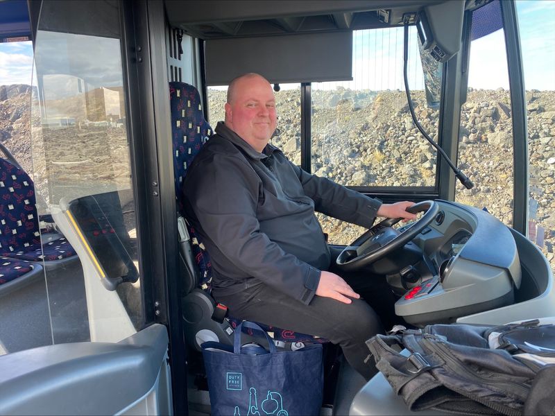 Das Bild zeigt Sigurbjörn Arnar Jónsson, einen Busfahrer, am Steuer des Busses.