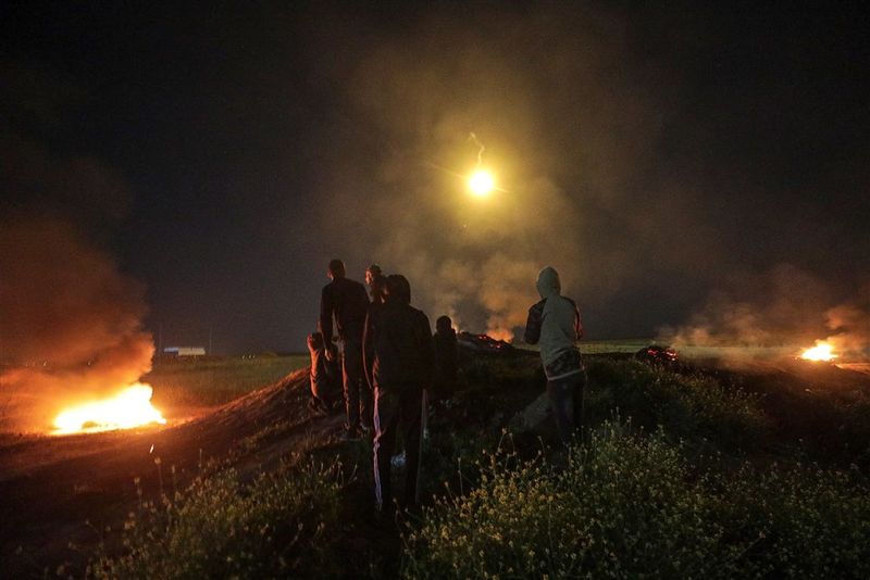 Hópur Palestínumanna fylgist með ferðum eldflaugar sem skotið var frá Gaza í átt til Ísraels snemma morguns 5. apríl 2023. Allt umhverfis brenna hjólbarðar en ísraelski flugherinn gerði loftárásir á Gaza í kjölfar eldflaugaskotanna þaðan.