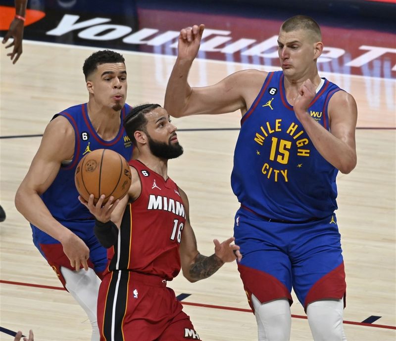 Caleb Martin, framherji Miami Heat (í miðið) býr sig undir að kasta boltanum í körfu, umkringdur Michael Porter Jr., sóknarmanni Denver Nuggets (til vinstri) og miðherjanum Nikola Jokic (til hægri), í fyrsta fjórðungi fyrsta leiks liðanna í úrslitakeppni NBA körfuboltadeildarinnar 1. júní 2023.