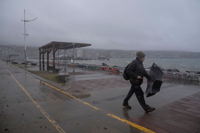A person with umbrella walks on a promenade in Valparaiso, Chile, 13 June 2024. Dozens of people lost their homes after the continuous rainfall since 11 June which has caused flooding and problems with the electricity services, leading to suspension of classes in schools and universities.