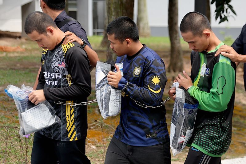 Three members of Global Ikhwan Services and Business Holdings (GISBH) escorted by Royal Malaysian Police officers depart after facing charges at a court in Seremban, Malaysia, 19 September 2024. The three suspects, detained during recent operations related to the raid of 20 welfare homes allegedly linked to GISBH, will be charged under Sections 14(a) and 14(b) of the Sexual Offenses Against Children Act 2017 (Act 792). The raid resulted in 171 arrests for 'neglect and mistreatment' of children, according to a police statement from 11 September.