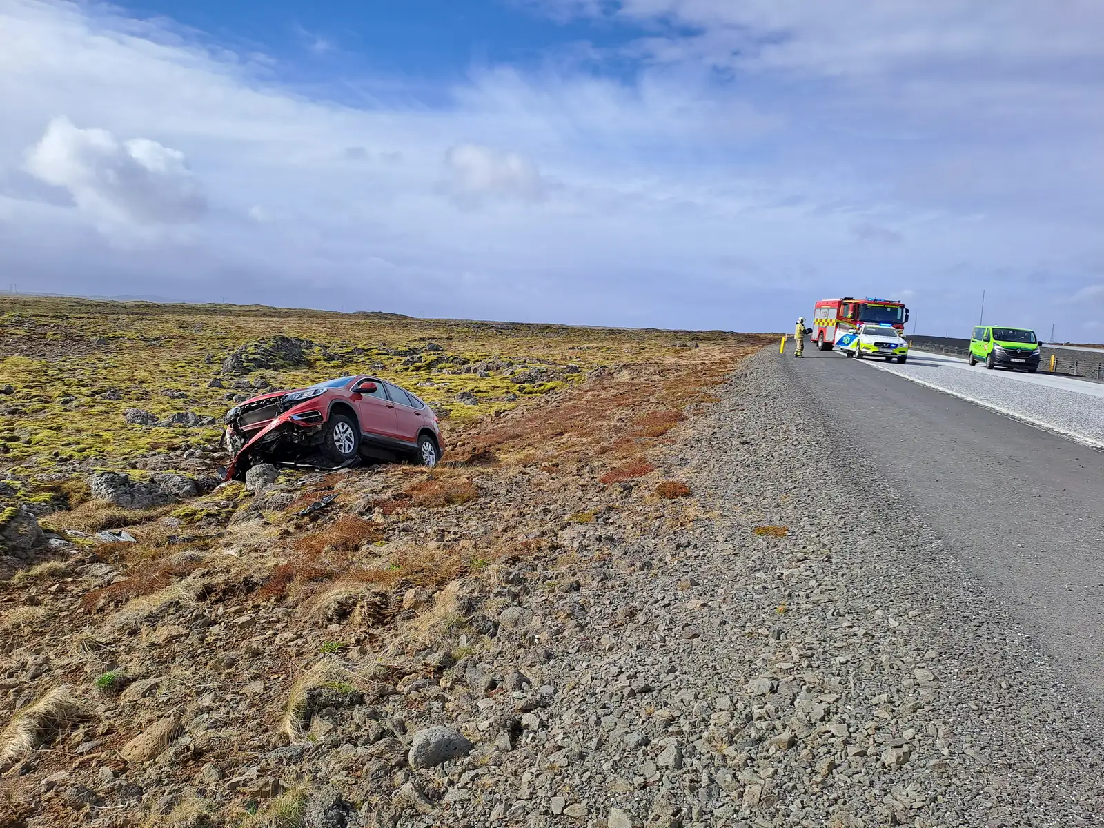 Mynd af bíl sem ók út af veginum við Kúagerði. Í bakgrunni eru bílar frá viðbragðsaðilum.