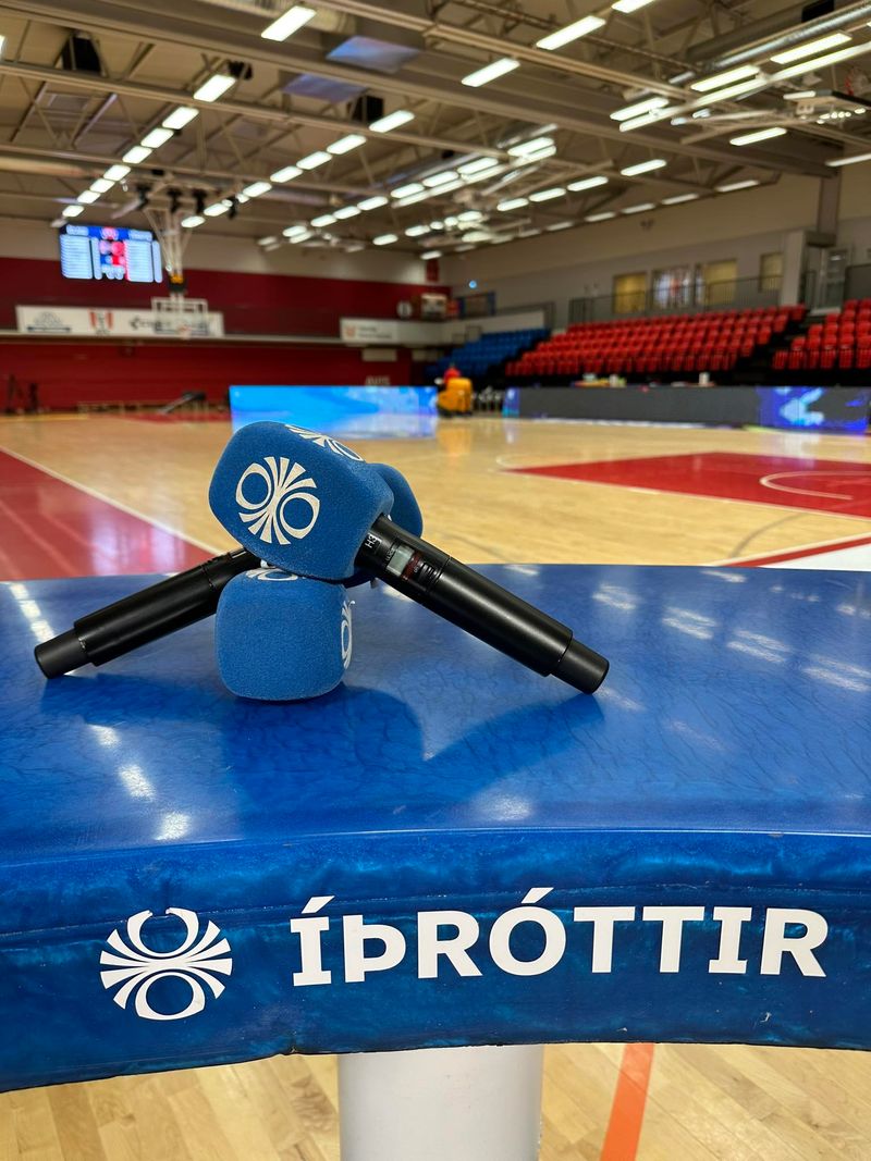 Tveir hljóðnemar sjást í forgrunni og Ólafssalur í bakgrunni. Útsendingarsett íþróttadeildar RÚV sést.
